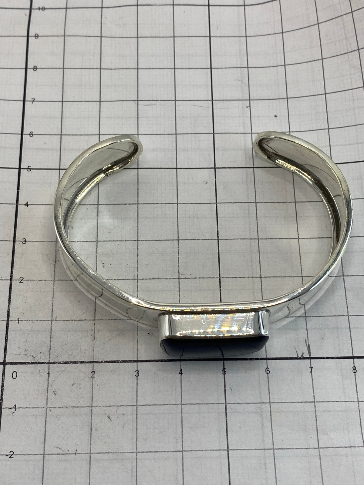 Brazalete sobre fondo blanco con medidor de escala, mostrando la piedra ónix y el Quinto 925