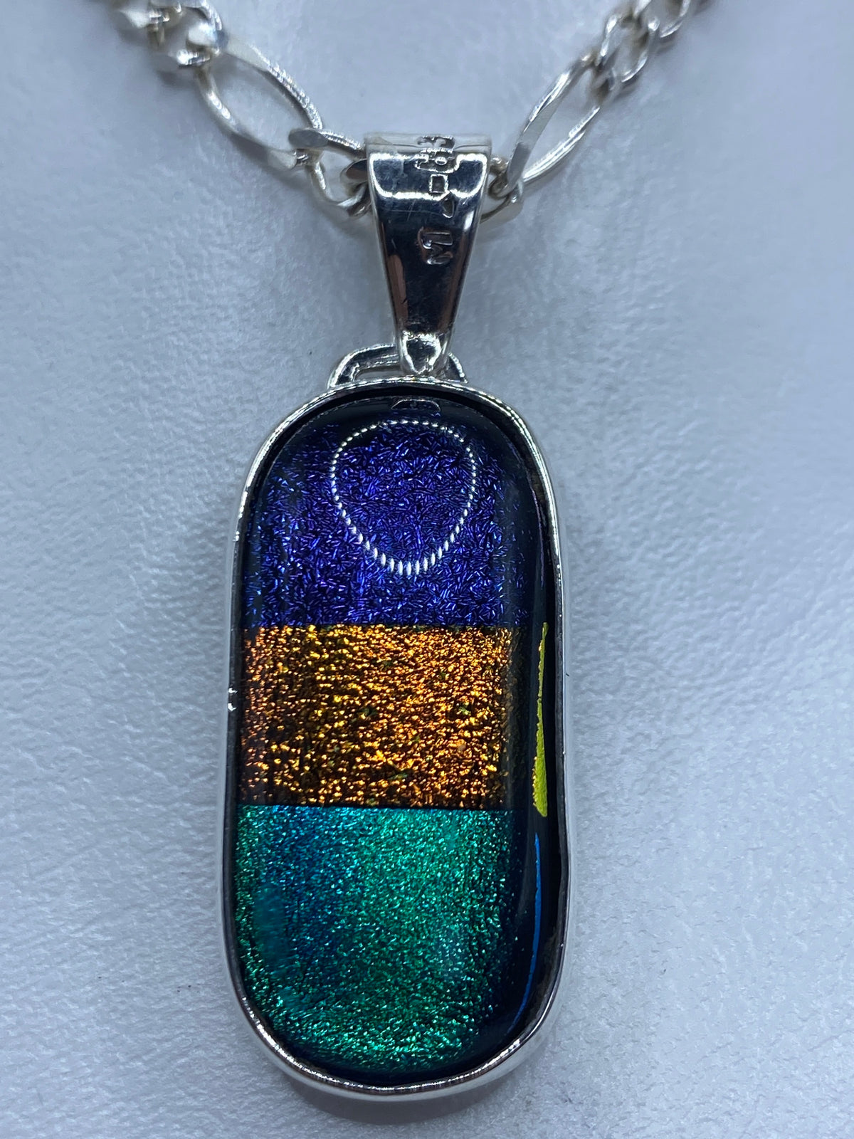 Dije de plata con incrustación tricolor: azul, dorado y verde turquesa en cadena plateada