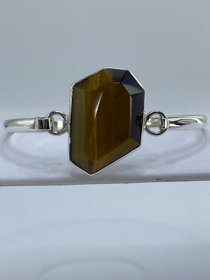 Brazalete puesto en muñeca de mujer, piedra Ojo de Tigre visible en posición central