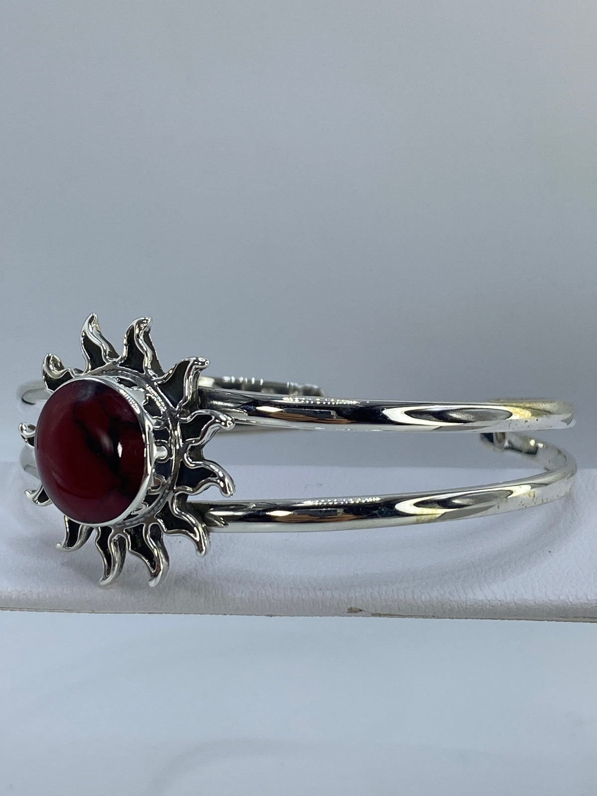 Detalle lateral del brazalete mostrando la banda ancha de plata y el coral rojo brillante