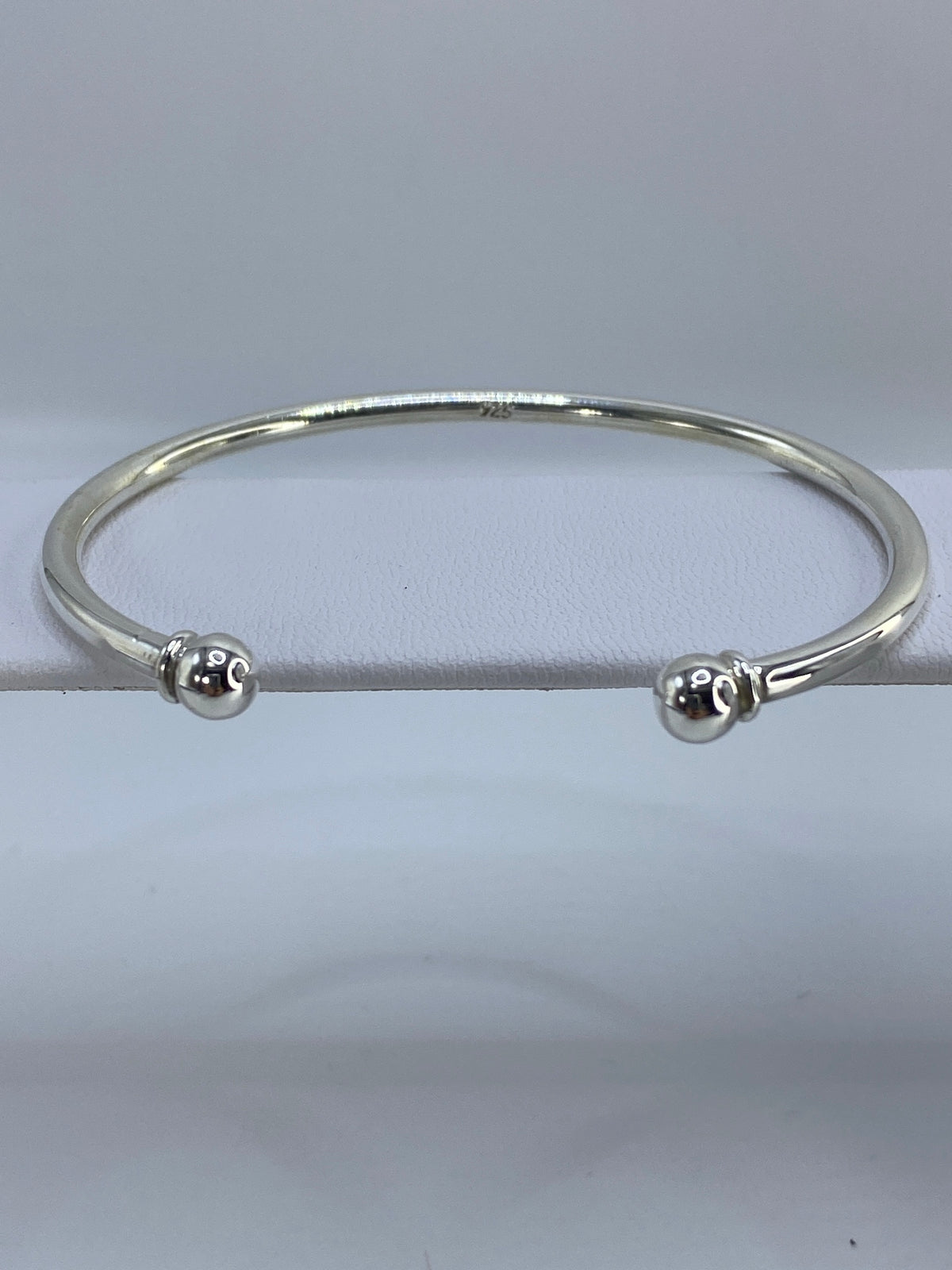 Brazalete de plata cartoneado en la muñeca, mostrando el volumen 3D de la técnica