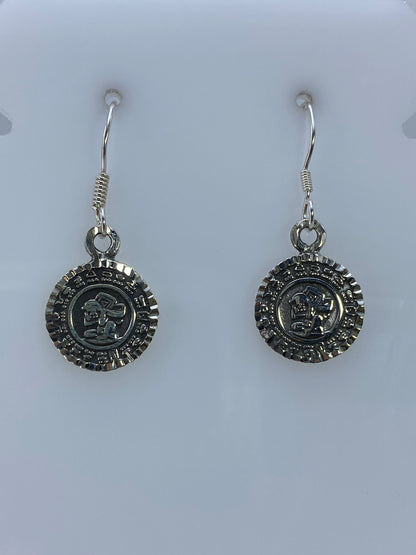 Detalle frontal de los aretes prehispánicos mostrando el relieve martillado del Calendario Azteca
