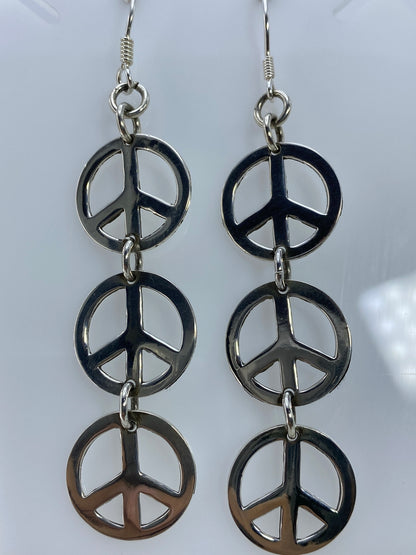 Par de aretes de plata con símbolo de paz calado, colgando en forma simétrica