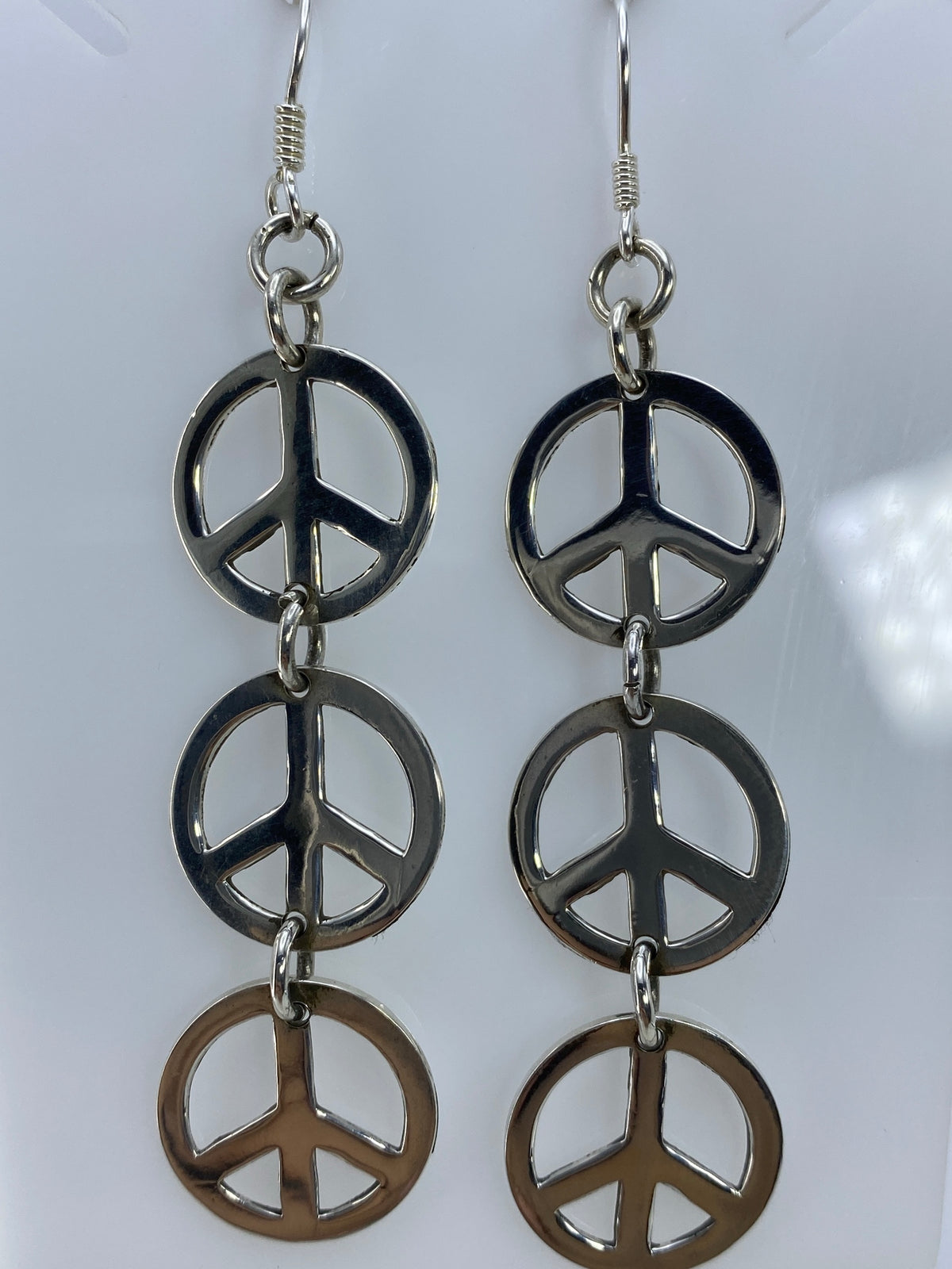 Aretes de paz sobre regla mostrando largo de 8.2 cm desde gancho