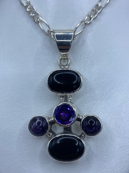 Dije cruz de plata 925 con ónix negro, amatista morada y circonia engastados, colgante sobre fondo blanco
