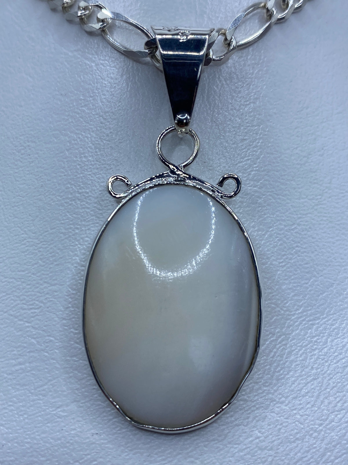 Dije ovalado de plata 950 con perla blanca engastada, colgando de una cadena de eslabones