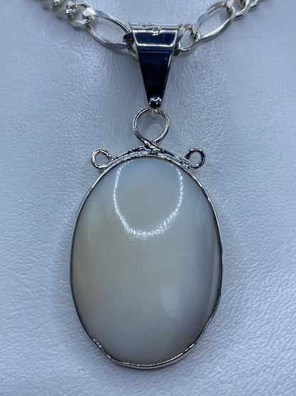 Dije ovalado de plata 950 con perla blanca engastada, colgando de una cadena de eslabones
