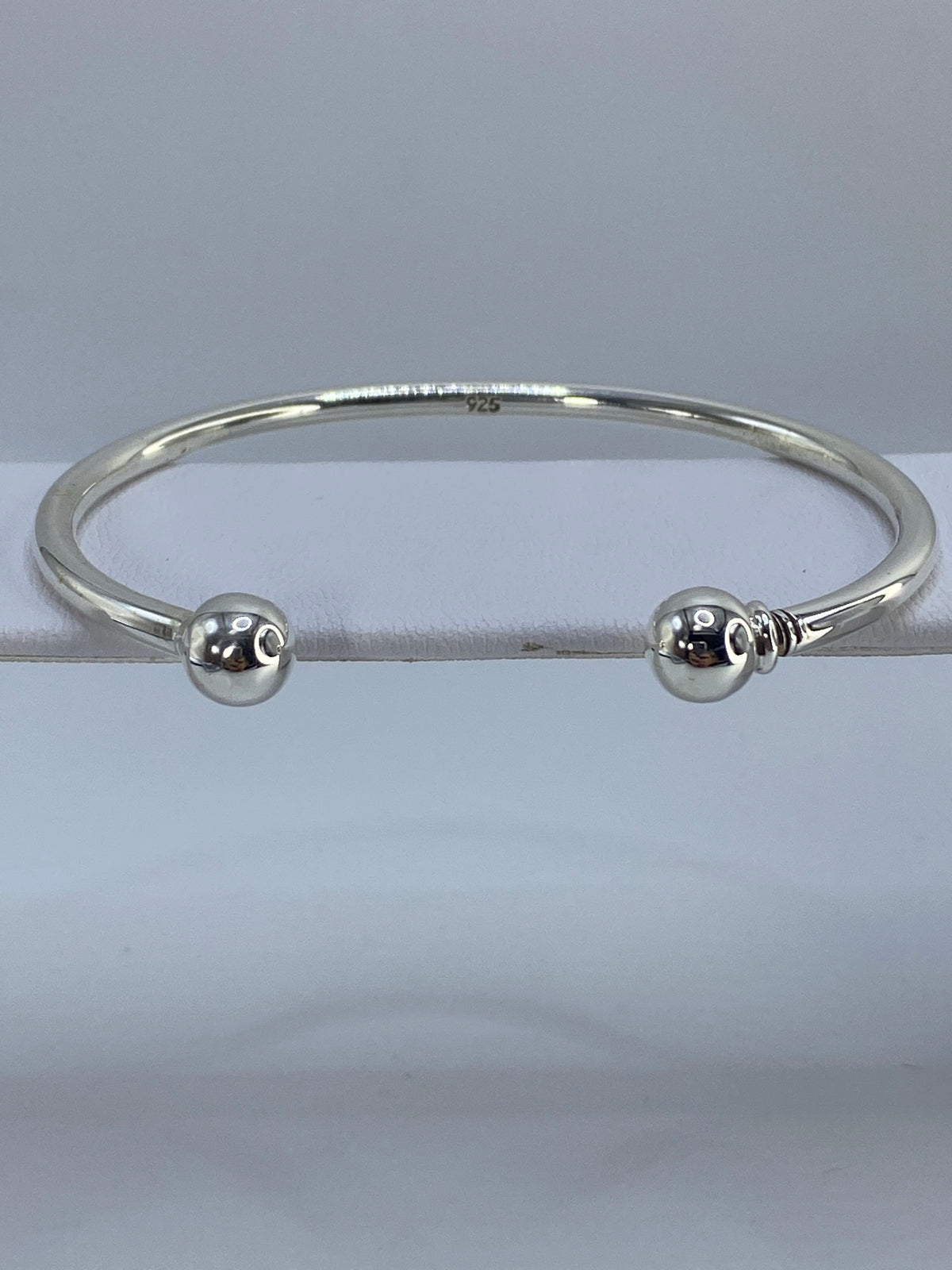 Brazalete de plata cartoneado puesto en la muñeca, mostrando el volumen 3D y el diámetro interior