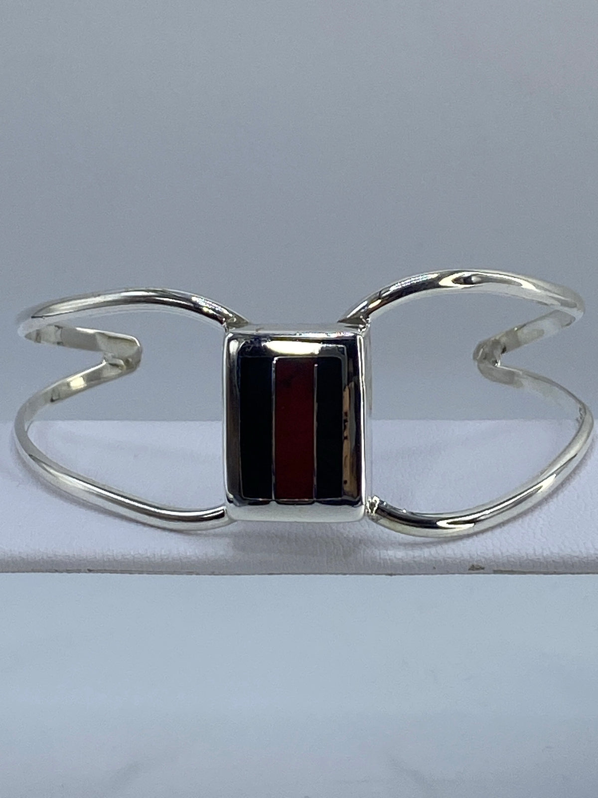 Brazalete de plata rígido con coral rojo e ónix negro en la muñeca de una mujer