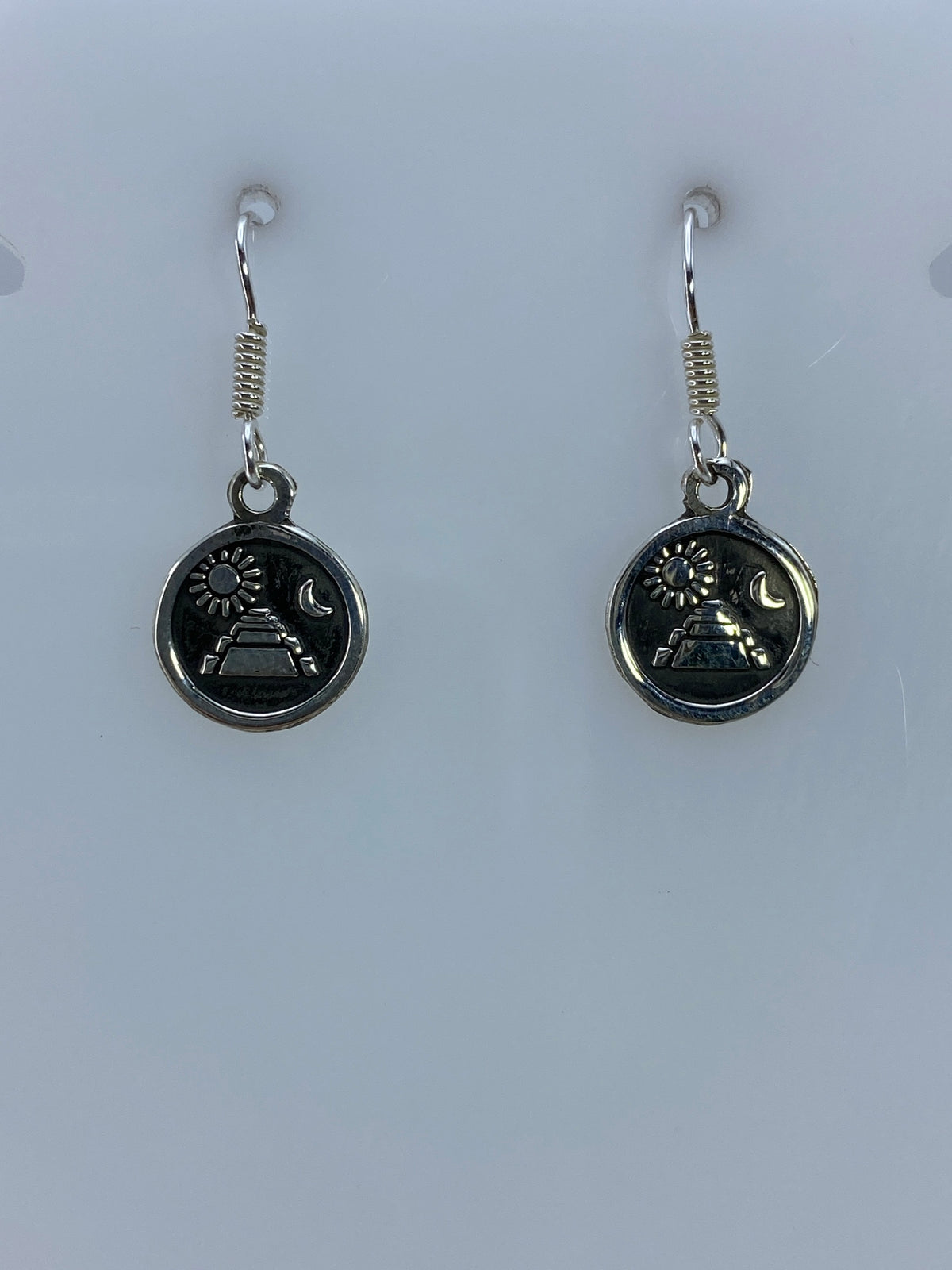 Detalle del repujado en cada arete mostrando la pirámide, sol y luna