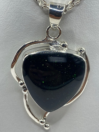 Dije corazón de plata 950 con piedra verde engastada, colgando de cadena de eslabones