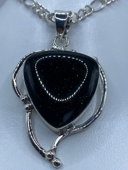 Vista frontal detallada del corazón de plata con la piedra verde en el centro