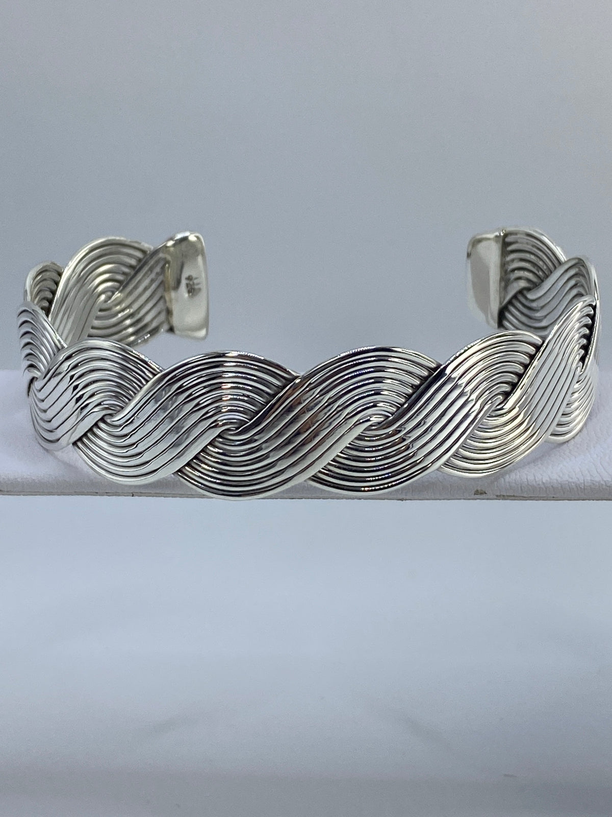 Brazalete de plata cartoneado con ondas profundas, puesto en la muñeca