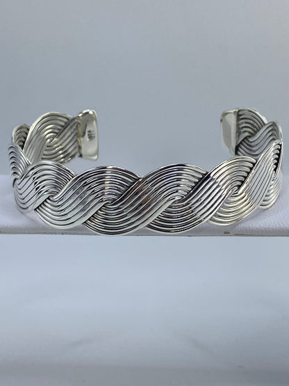 Brazalete de plata cartoneado con ondas profundas, puesto en la muñeca