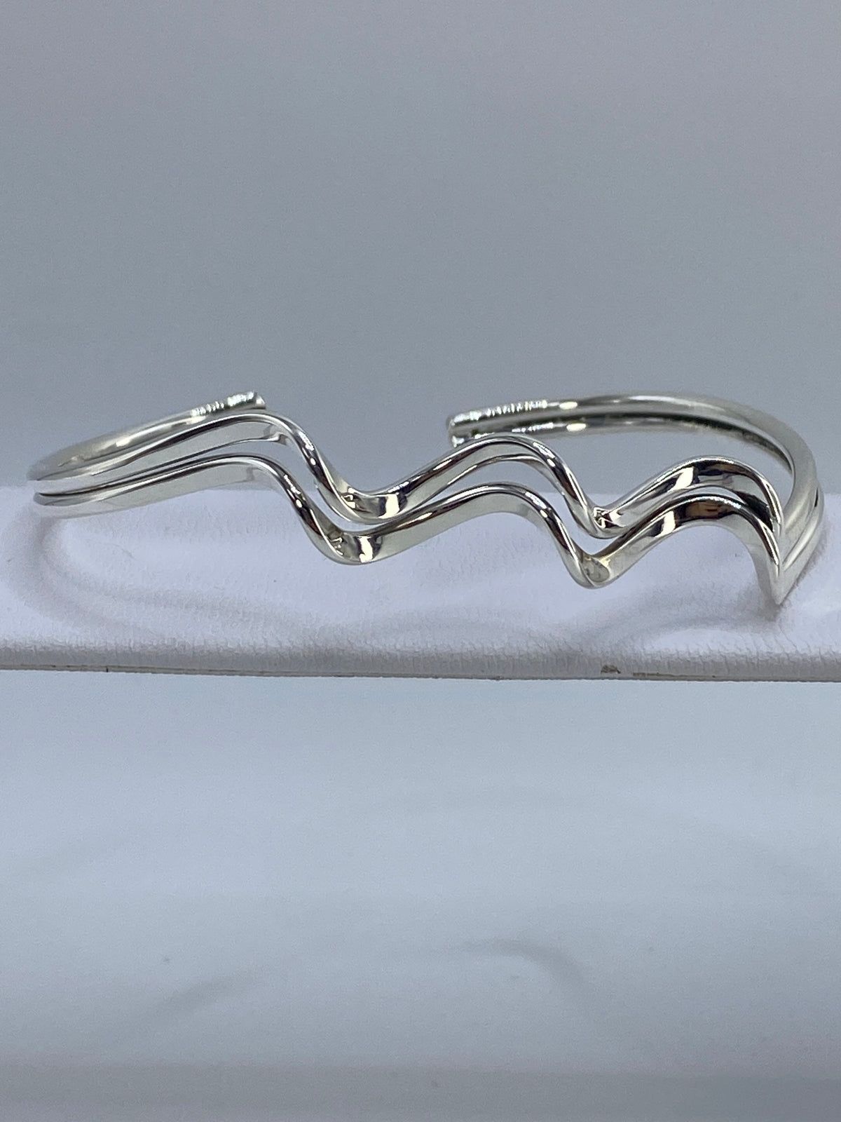 Brazalete rígido de plata 925 en cartoneado visto de arriba sobre fondo blanco