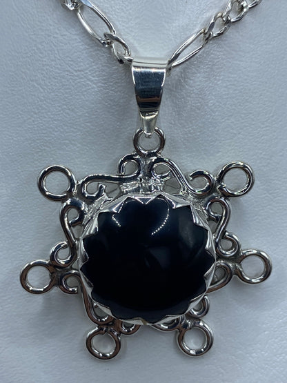 Detalle frontal del dije mostrando el ónix negro brillante y los anillos filigranados