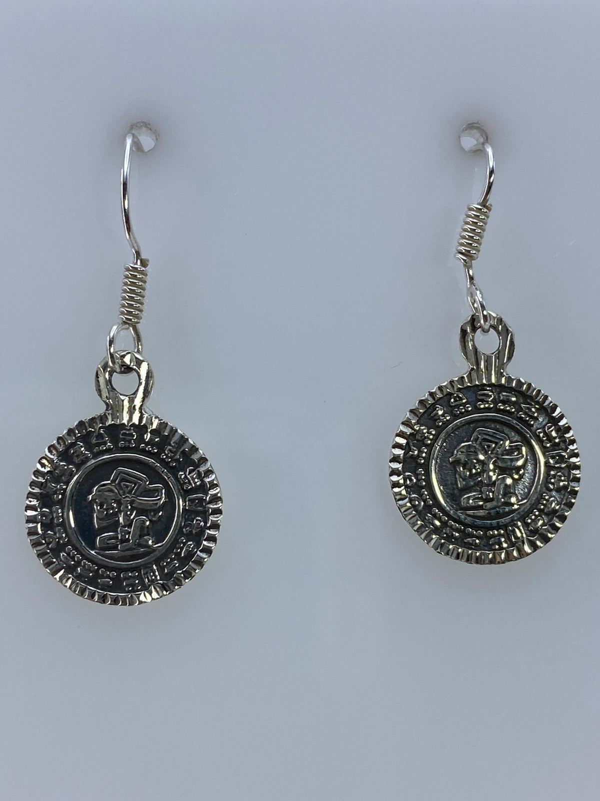 Aretes de plata 925 repujado con diseño prehispánico colgando de gancho de plata