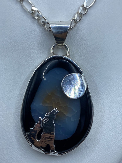 Vista frontal del dije lobo y luna mostrando el relieve y el engaste de onix