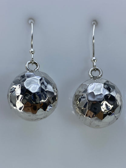 Par de aretes de plata cartoneado con diseño facetado, vistos de frente sobre fondo gris
