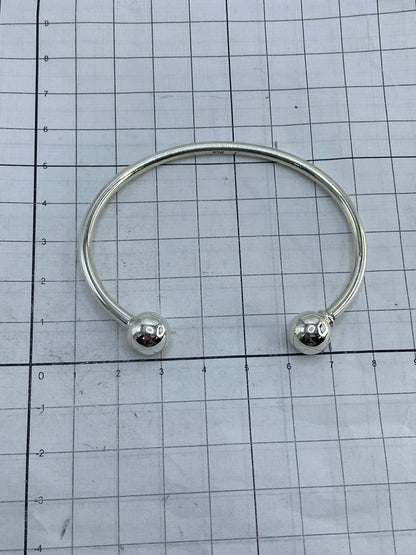 Brazalete rígido de plata sobre fondo blanco con el Quinto 925 visible