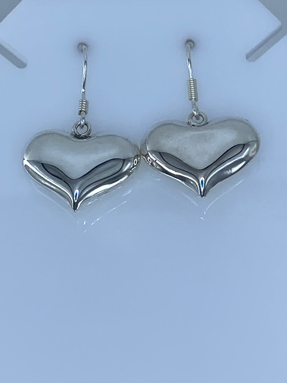 Aretes de corazón de plata 925 en cartoneado, vista frontal mostrando el volumen y pulido