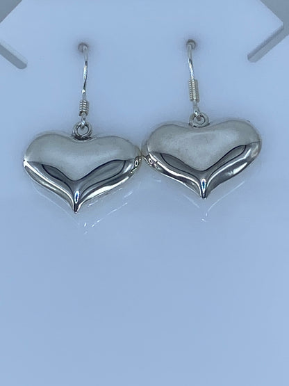 Aretes de corazón de plata 925 en cartoneado, vista frontal mostrando el volumen y pulido