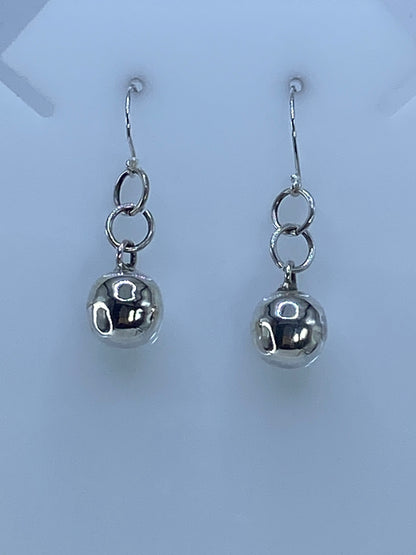 Par de aretes de plata con diseño geométrico cartoneado, colgando de ganchos