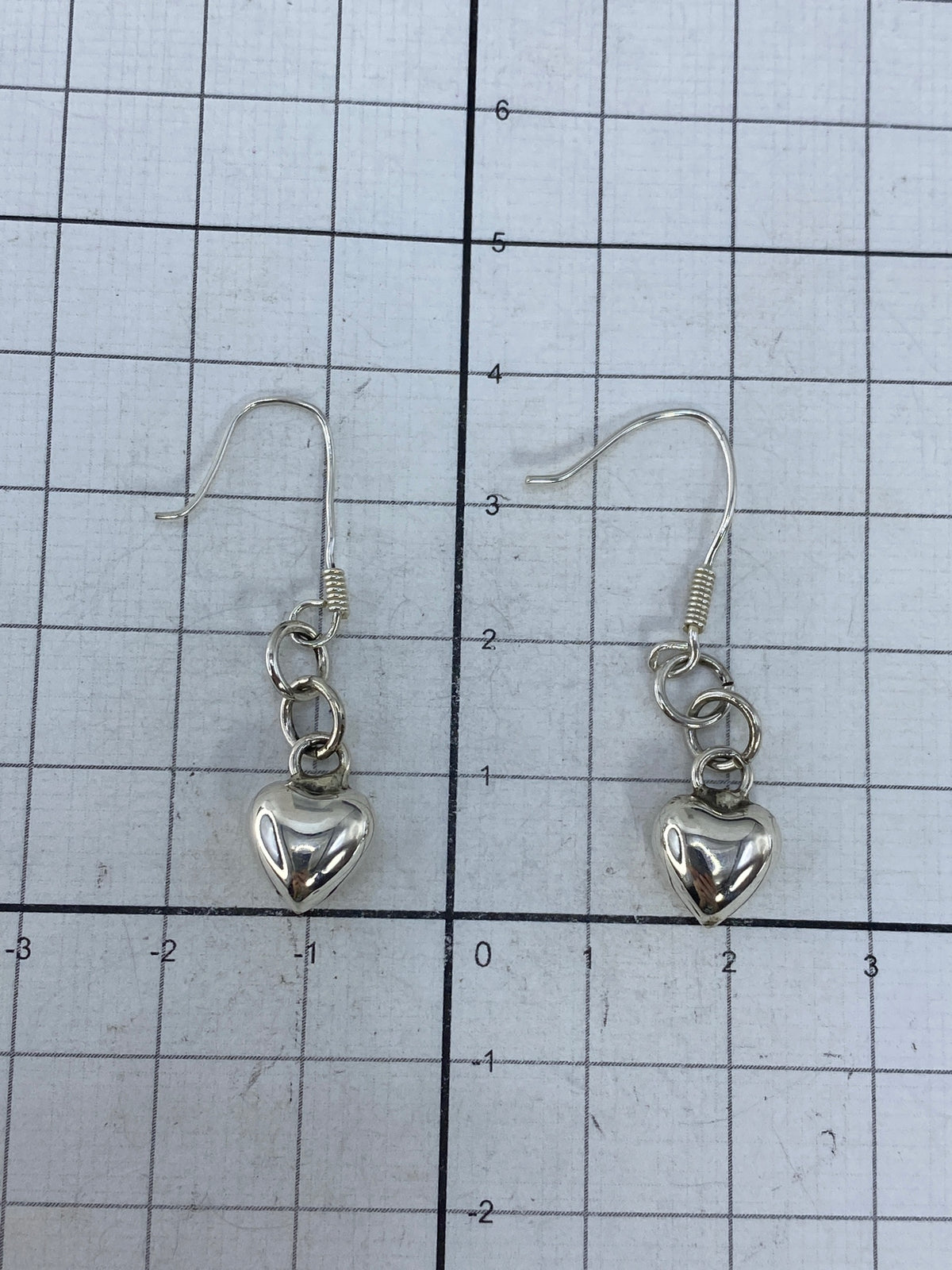 Par de aretes de corazón cartoneado en plata brillante, vista frontal