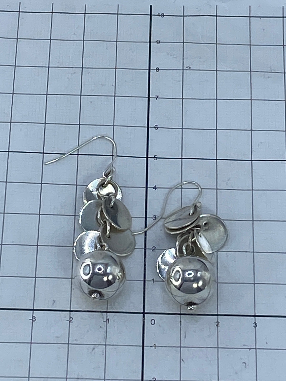 Aretes sobre fondo blanco con ganchos de plata 925 visibles y Quinto