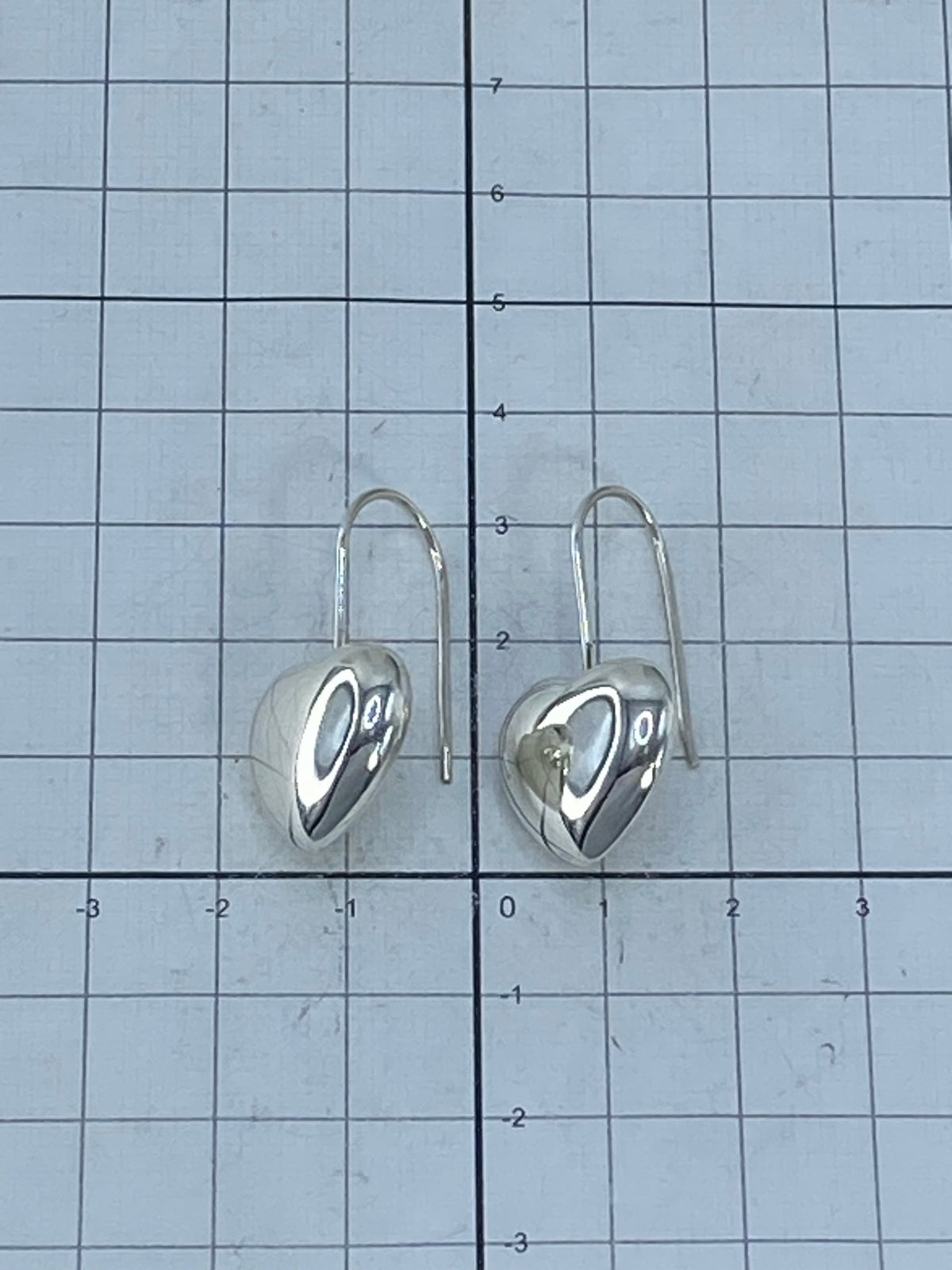 Aretes en gancho de plata sobre fondo azul mostrando el brillo del cartoneado