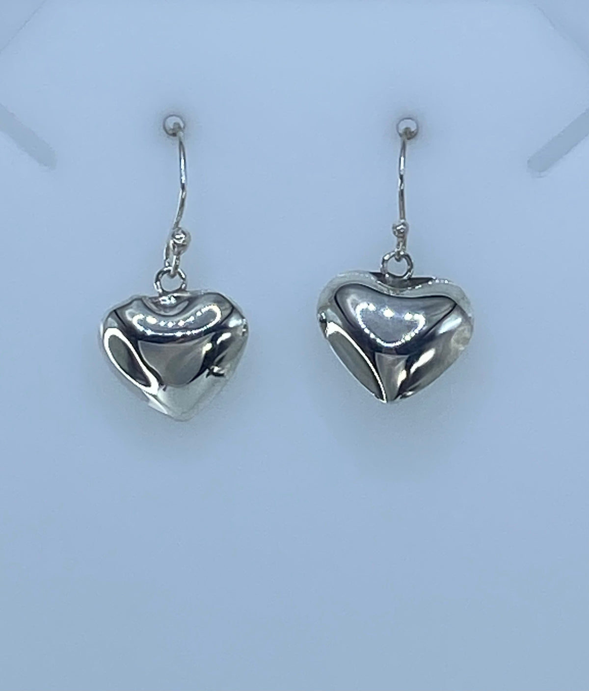 Detalle de un arete corazón de plata 925 mostrando el Quinto y el acabado pulido