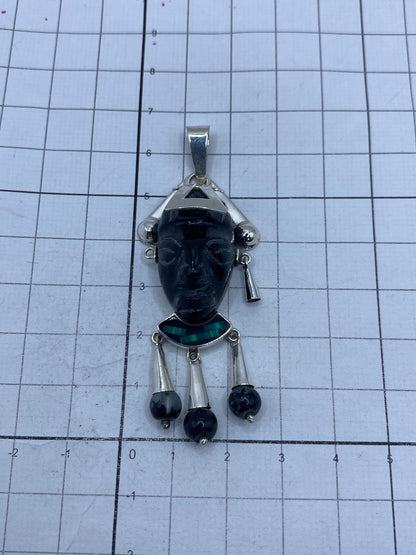 Dije de 6.7 cm sobre escala de medición, con tres perlas de ónix colgantes