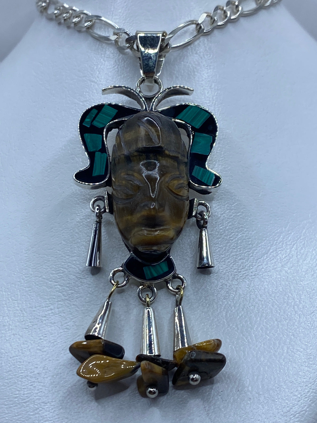 Detalle frontal del repujado artesanal del rostro del rey prehispánico en plata 925