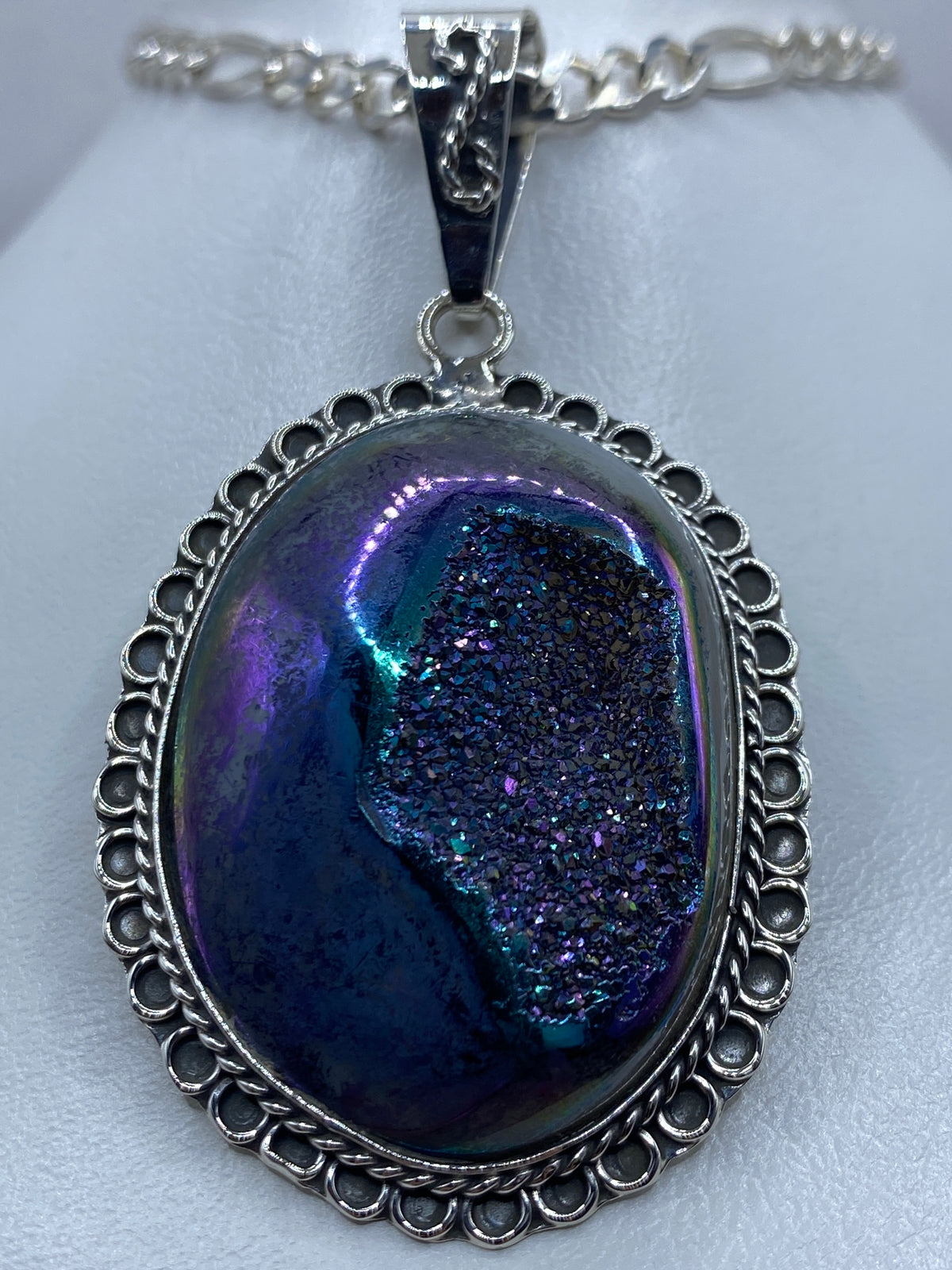 Detalle frontal del dije de piedra morada mostrando el engaste a mano y el marco calado