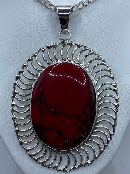 Vista frontal del dije de coral rojo de 8.4 cm de largo, detalle del engaste a mano