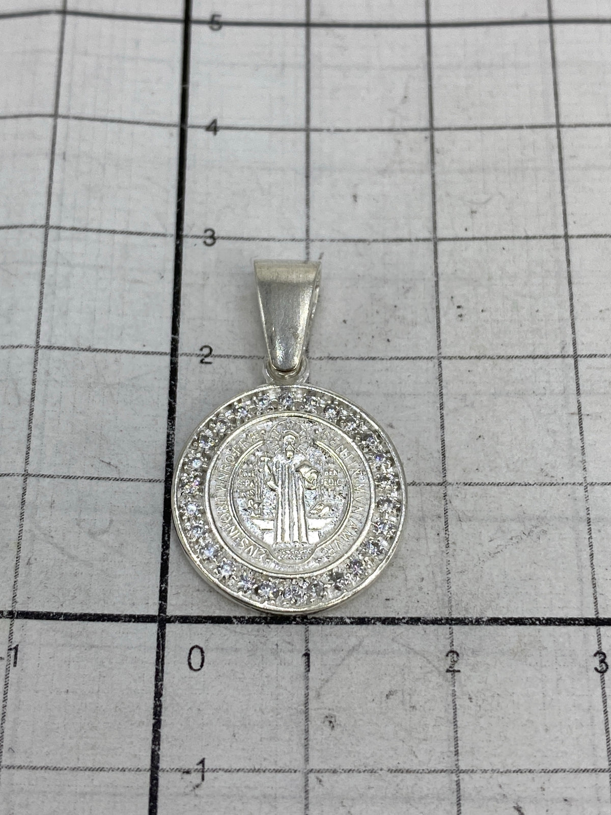 Medalla San Benito sobre regla mostrando 2.7 cm de largo, dije sin cadena
