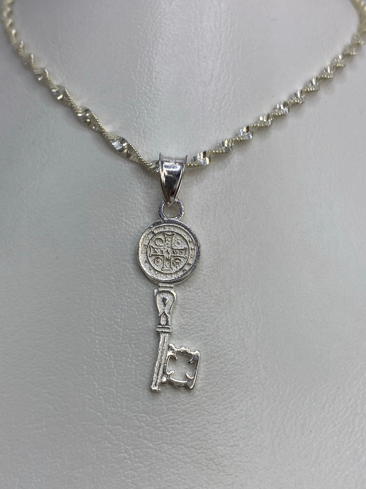 Detalle frontal de la Medal de San Benito con diseño religioso fundido