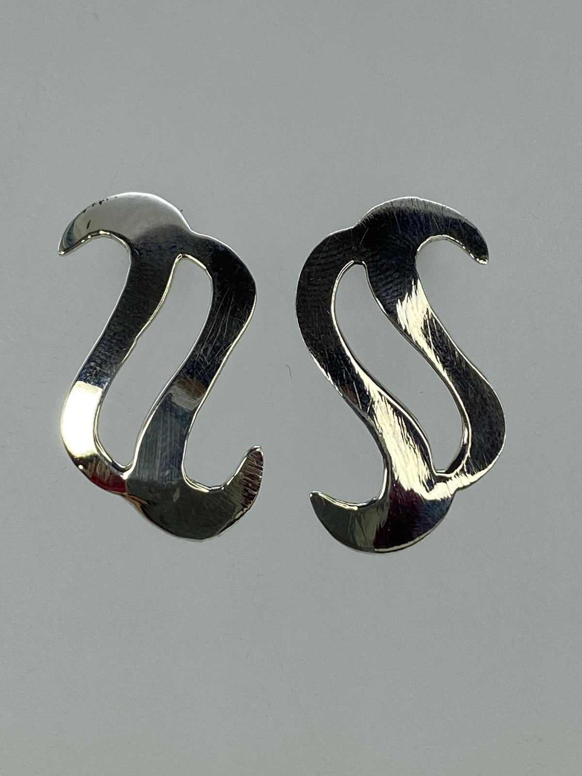 Aretes de plata 925 sobre superficie neutra mostrando el Quinto