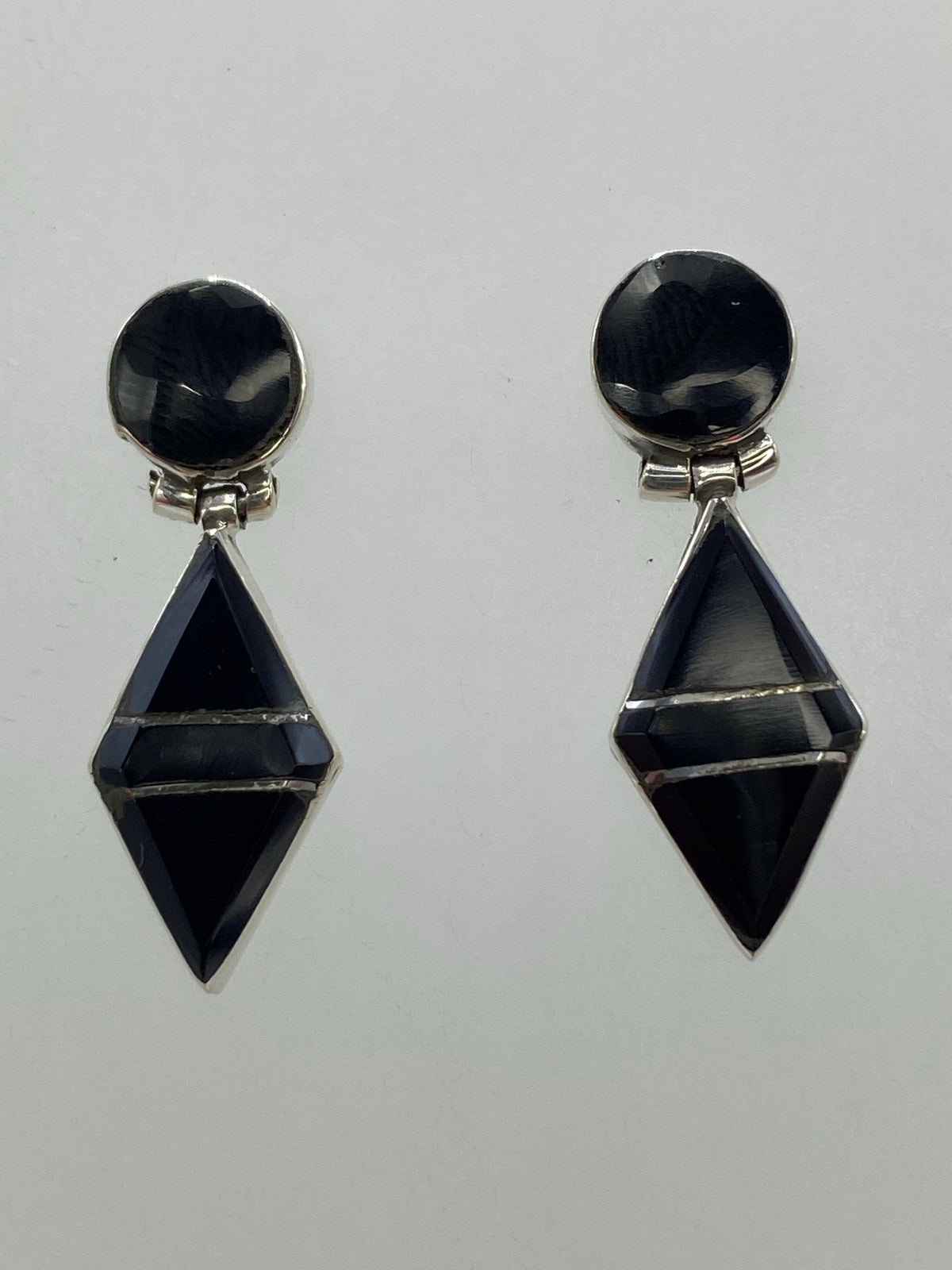 Par de aretes de plata con ónix negro en diseño geométrico esfera-diamante, vista frontal