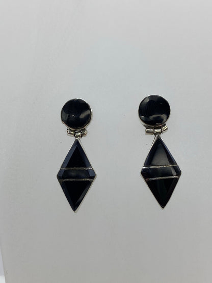 Aretes de plata 950 con ónix negro sobre fondo gris, detalle del engaste a mano