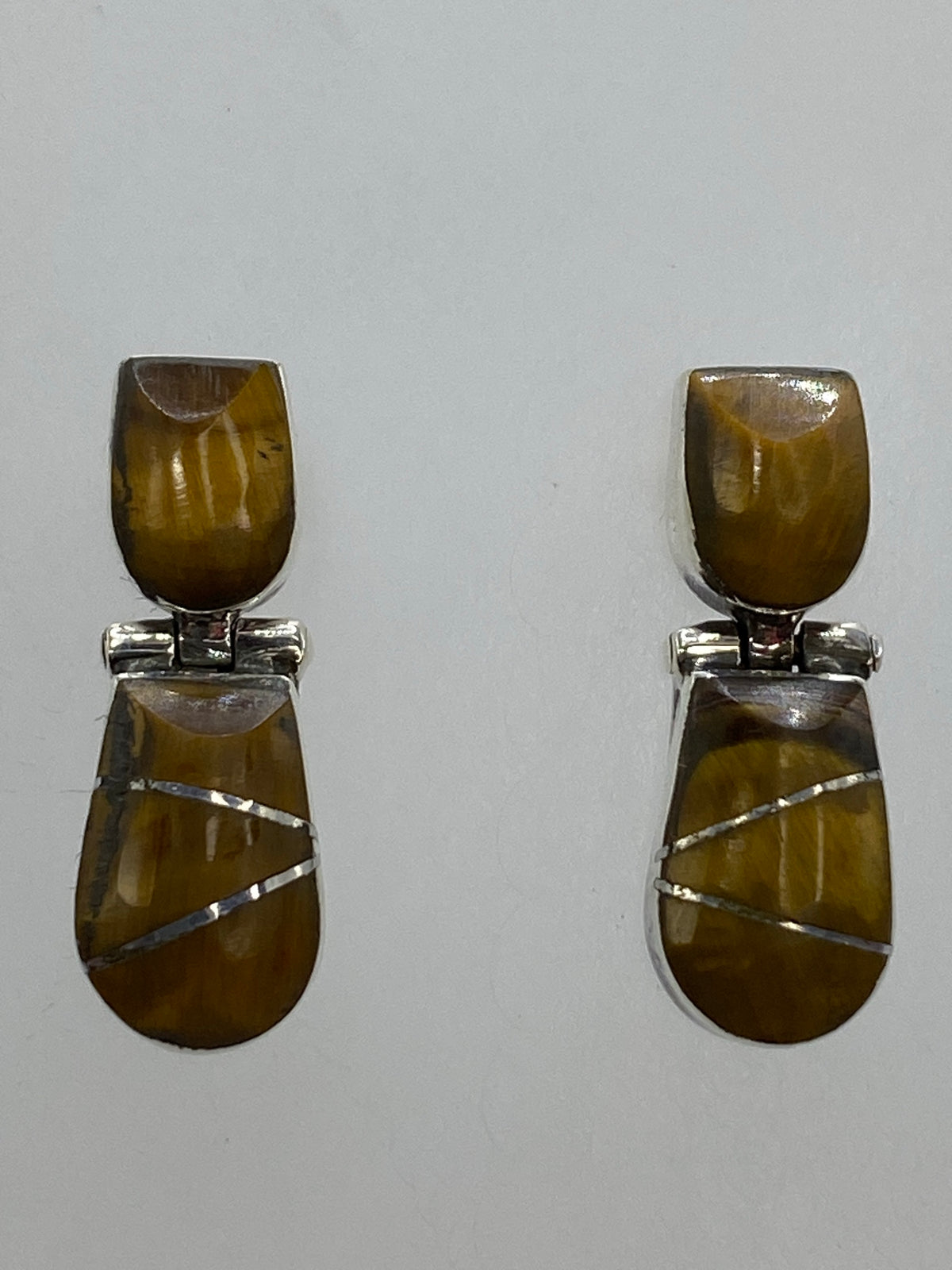 Detalle frontal de los aretes con piedra Ojo de Gato en tono café