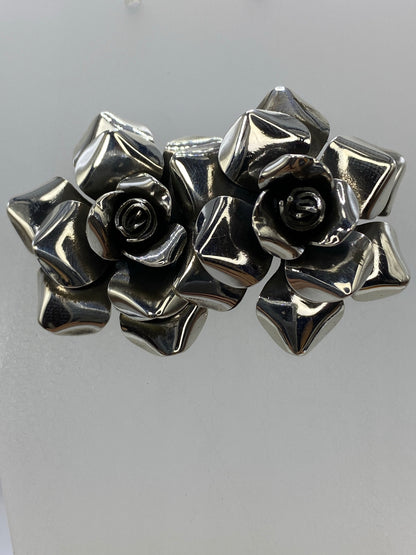 Aretes de plata con flores en relieve, mostrando los pétalos martillados a mano