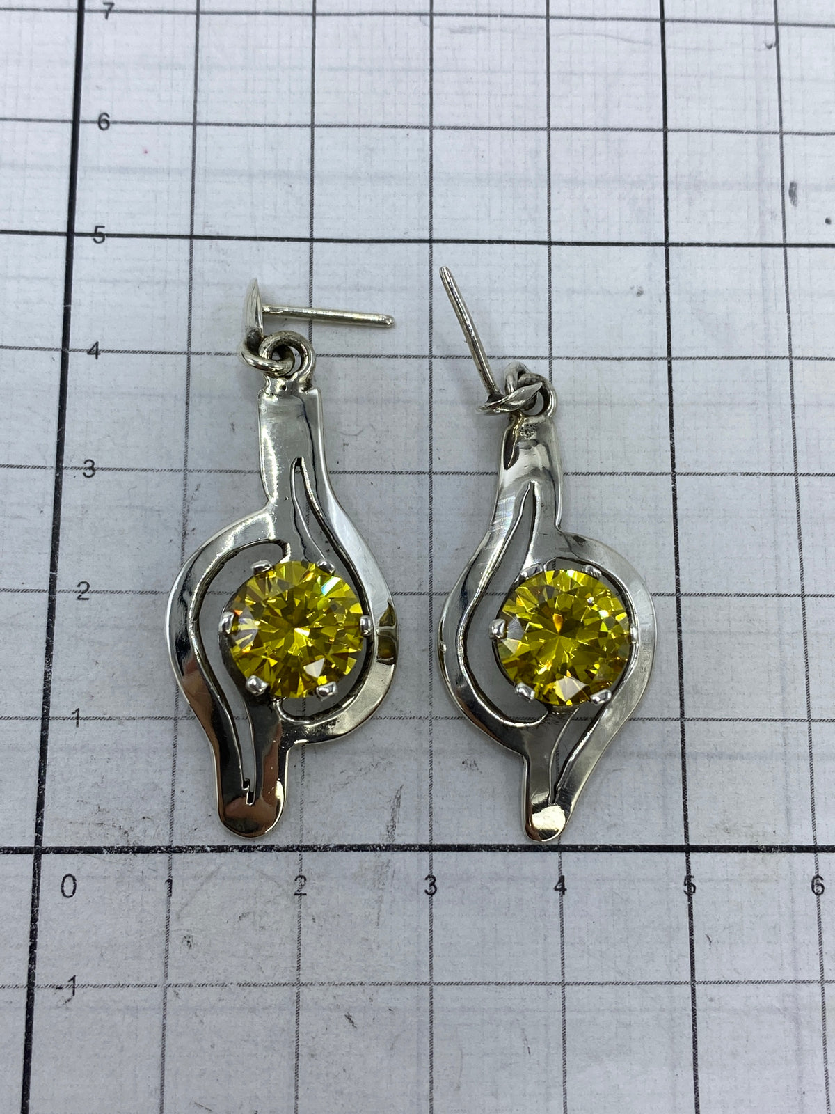 Aretes sobre fondo blanco con escala de centímetros, mostrando largo de 3.5 cm