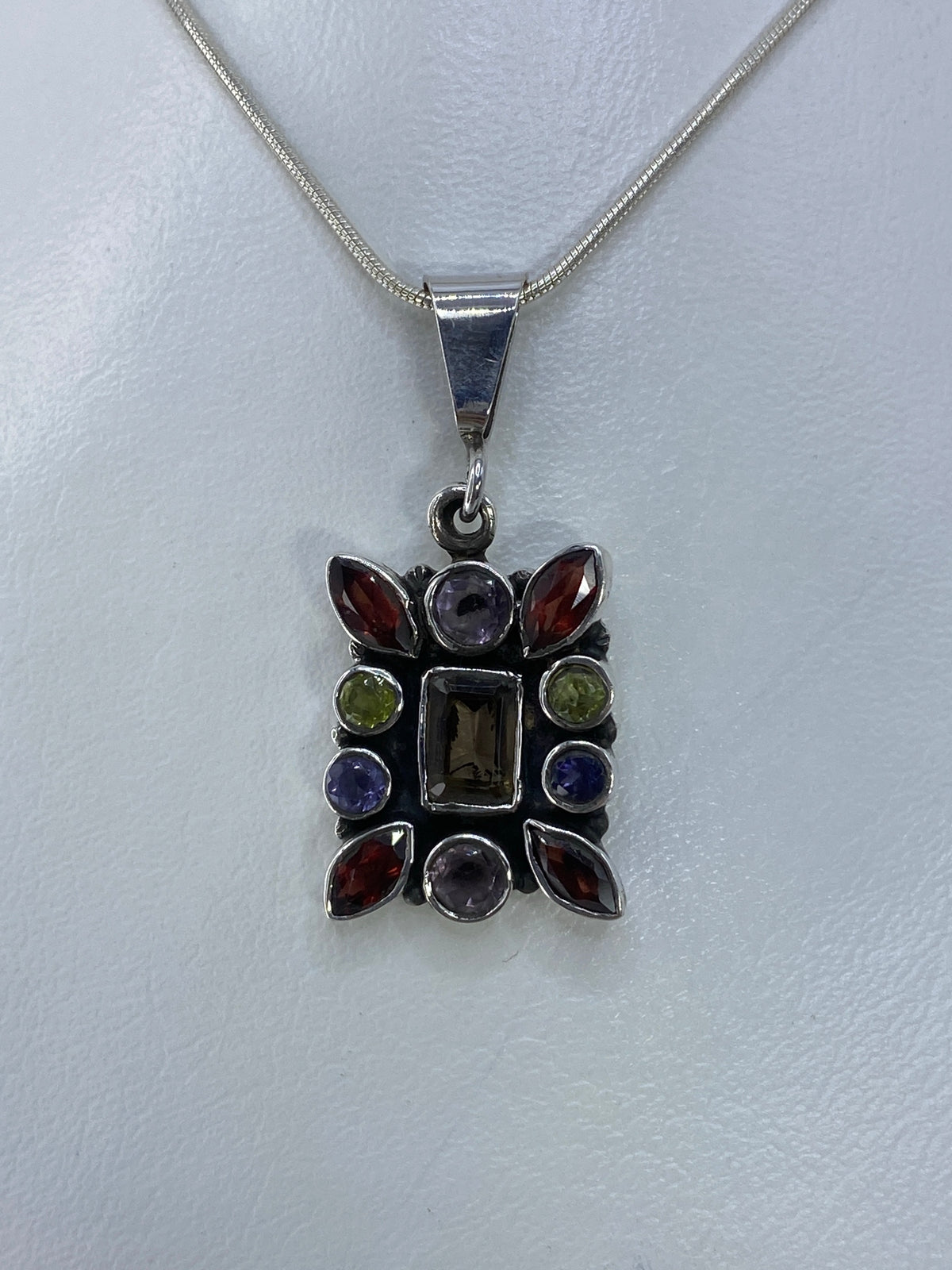 Dije de plata con circonia multicolor en marco geométrico colgando de cadena de plata