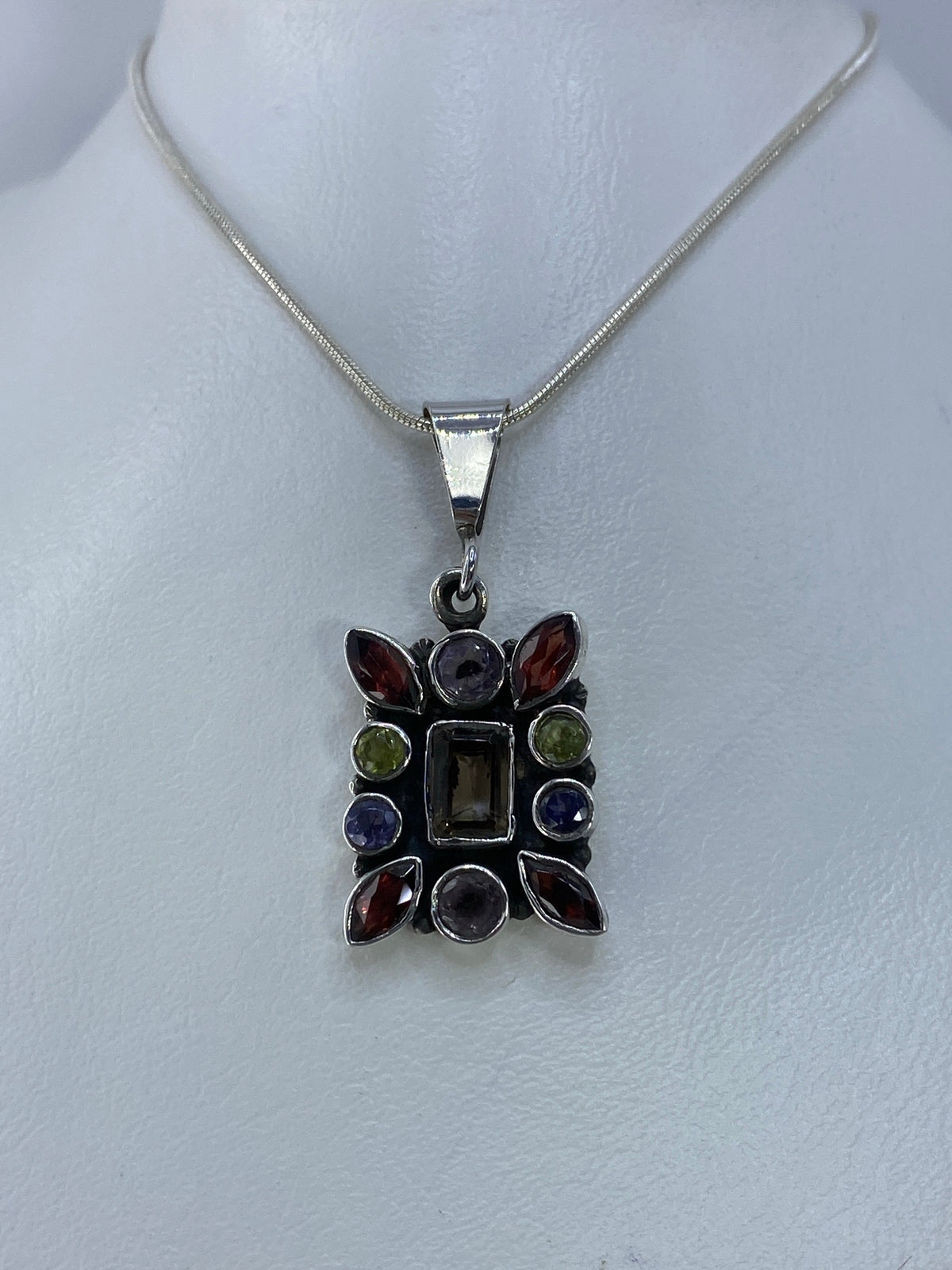 Vista frontal del dije de plata 925 con circonia roja, morada, verde y amarilla