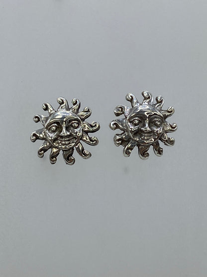 Aretes de plata sol sonriente sobre fondo gris, lado izquierdo y derecho