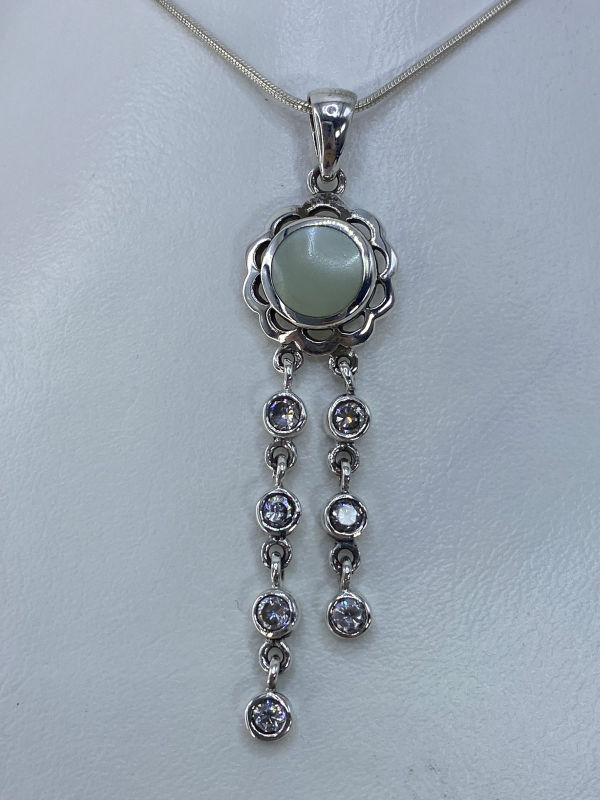 Dije de plata con perla blanca y circonia en forma de flor, colgando de cadena serpentín