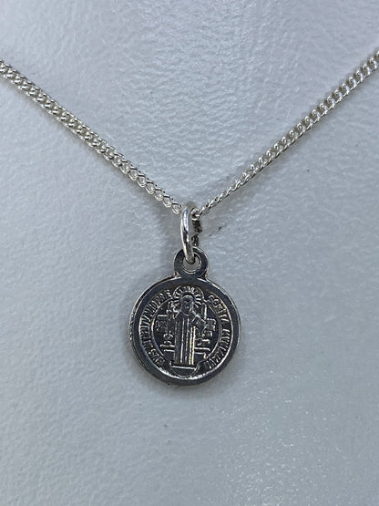 Reverso del dije de San Benito con inscripción y cruces grabadas en plata