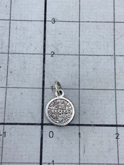 Dije San Benito junto a regla de medida mostrando tamaño de 1.3 cm de largo