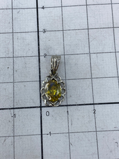 Dije de plata en fondo blanco mostrando el brillo de la circonia amarillo